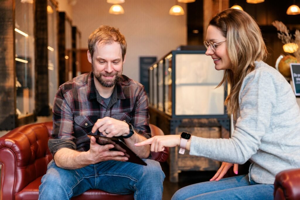 a man and a woman sitting on a couch looking at a tablet as an example of how to showcase a WordPress Portfolio without many clients